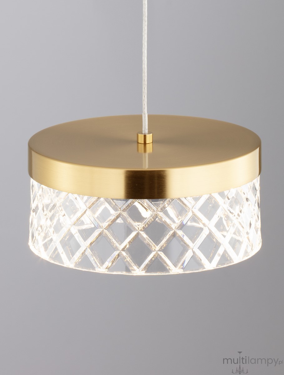 Lampa wisząca Mineros z pojedynczym źródłem LED 6W. Złota, okrągła podsufitka z gładkiego metalu, przezroczysta klosz z kryształowym wzorem w romby. Zawieszona na białym przewodzie, idealna do nowoczesnych wnętrz.