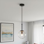 Lampa wisząca Sebia z czarnym metalowym mocowaniem i przezroczystym kulistym kloszem. Ujęcie z dołu, lampa zawieszona na cienkim przewodzie. W tle widoczny obraz w ramie oraz zasłony. E14, 1x żarówka.