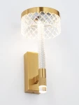 Kinkiet Mineros 1xLED 8W w kolorze złotym, z przezroczystym kloszem w kształcie okręgu oraz cylindrycznym uchwytem z teksturą. Montowany na ścianie, emitujący ciepłe światło. Tło białe, minimalistyczne.