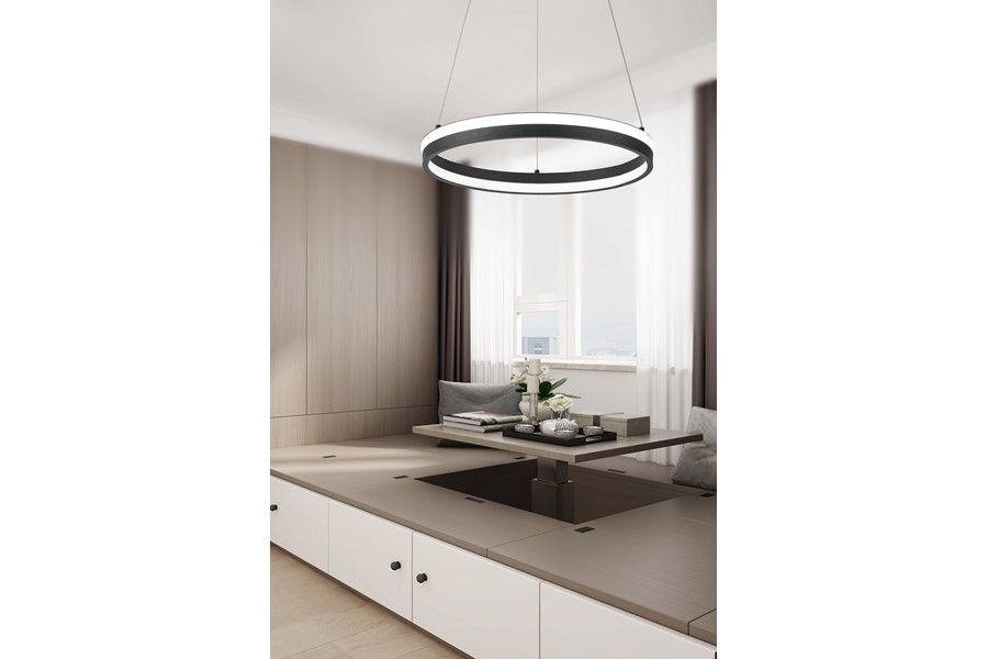 Lampa wisząca LED Proxima 32W CCT w kolorze czarnym, okrągła, zawieszona na cienkich linkach. Umieszczona w nowoczesnym wnętrzu z drewnianymi i jasnymi elementami, obok stołu z dekoracjami i roślinami.