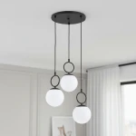 Lampa wisząca Sitro z trzema kloszami, każdy w kształcie białej kuli, zawieszona na czarnych linkach. Montaż sufitowy z okrągłą czarną podstawą. Prosty, nowoczesny design, idealna do wnętrz. Tło jasne, neutralne.
