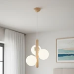 Lampa wisząca Kanet Black 3-punktowa w białym kolorze z naturalnym drewnem, z trzema okrągłymi kloszami. Ujęcie z dołu, wisząca, z metalowymi detalami. Tło w jasnym pomieszczeniu z zasłonami i obrazem.