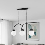 Lampa wisząca Darso 3xE14 w kolorze czarnym, z trzema okrągłymi kloszami z matowego szkła, zawieszona na dwóch łukowatych metalowych ramionach. Montaż sufitowy, umieszczona w nowoczesnym wnętrzu z jasnym tłem.