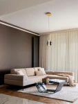 Lampa wisząca Morros 1xLED 8W w kolorze złotym, zawieszona na cienkim przewodzie, z okrągłym kloszem w odcieniu przezroczystym. Produkt znajduje się w nowoczesnym wnętrzu z jasną sofą i szklanym stołem na tle ciemnej ściany.