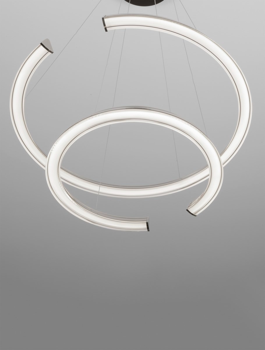 Lampa wisząca Orinoco z dwoma łukami w kolorze srebrnym, wykonana z materiału LED o mocy 70W. Ujęcie z góry, prezentujące nowoczesny design i subtelne podświetlenie. Zawieszona na cienkich linkach w minimalistycznym otoczeniu.