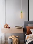 Lampa wisząca Perene 1xLED 9W w kolorze złotym i żółtym, z przezroczystym kloszem, zawieszona nad drewnianym stolikiem nocnym. W tle widoczne poduszki w odcieniach brązu i szarości oraz dekoracyjne akcesoria.