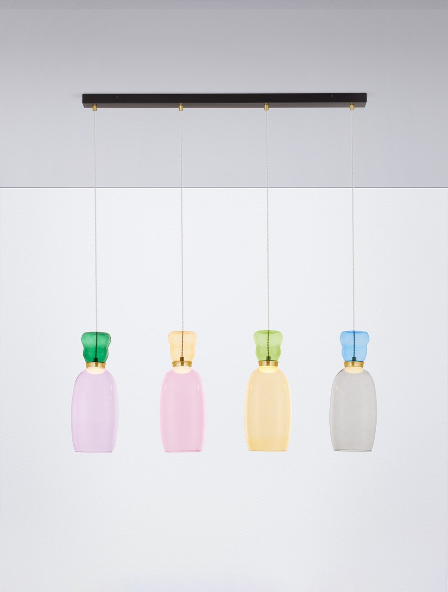 Lampa wisząca Perene z czterema kloszami LED w różnych kolorach: różowym, żółtym, zielonym i przezroczystym. Klosze mają zaokrąglony kształt, zawieszone na cienkich linkach z czarną metalową podstawą. Tło proste, białe.