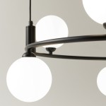 Czarna lampa wisząca Ring z sześcioma punktami świetlnymi. Metalowa konstrukcja z okrągłymi, matowymi kloszami w kolorze białym. Ujęcie z bliska, ukazujące detale mocowania i kształt kloszy.