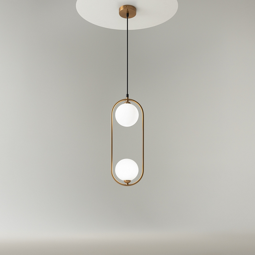 Lampa wisząca 2-punktowa w mosiężnej oprawie, z dwoma okrągłymi, białymi kloszami. Produkt zawieszony na czarnym przewodzie, umieszczony na jasnym tle. Kształt lampy podkreśla nowoczesny design.