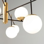 Lampa wisząca Nostalgia 9-punktowa w kolorze złotym. Konstrukcja z metalowymi ramionami i białymi, okrągłymi kloszami. Widok z bliska, ukazujący detal mocowania i kształt kulistych kloszy. Tło jednolite, jasne.