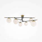 Lampa sufitowa Nostalgia 6-punktowa w kolorze złotym, z sześcioma białymi kulami ze szkła, zamontowana na czarnym stelażu. Kule umieszczone na asymetrycznych ramionach, pod kątem, co nadaje nowoczesny charakter. Tło białe.