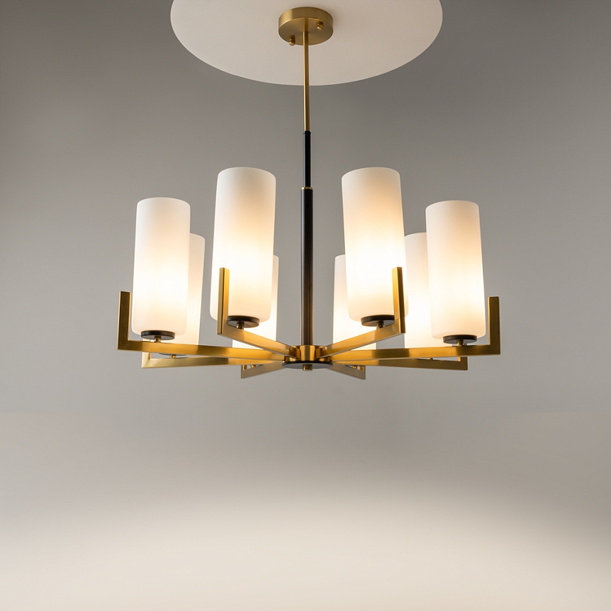 Lampa wisząca Fortano MOD089PL-08BS z ośmioma mlecznymi kloszami w kształcie cylindrów, zawieszona na złotej konstrukcji. Klosze umieszczone na ramionach w układzie promienistym, wisi pod okrągłym, metalowym mocowaniem. Tło szare, minimalistyczne.