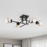 Lampa sufitowa Transfer 4-punktowa, czarna. Konstrukcja z metalowymi ramionami i szklanymi kloszami w kolorze bursztynowym. Ujęcie z góry, produkt zamontowany na suficie, w tle jasne wnętrze z zasłonami.