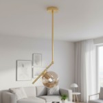 Lampa wisząca Liberty 1-punktowa w kolorze złotym z przezroczystą kulistą kloszem. Zawieszona na długim, prostym stelażu, w aranżacji wnętrza z szarym sofą i obrazami na ścianie.