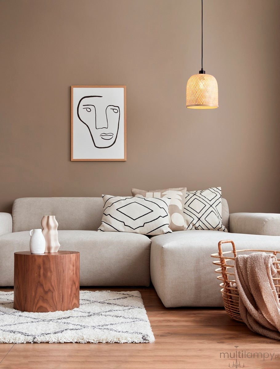 Lampa wisząca Talitas 1xE27 w kolorze czarnym, o kształcie cylindrycznym, zawieszona na cienkim przewodzie w nowoczesnym wnętrzu. W tle widoczna kanapa z poduszkami oraz dekoracje na stoliku i koszu.