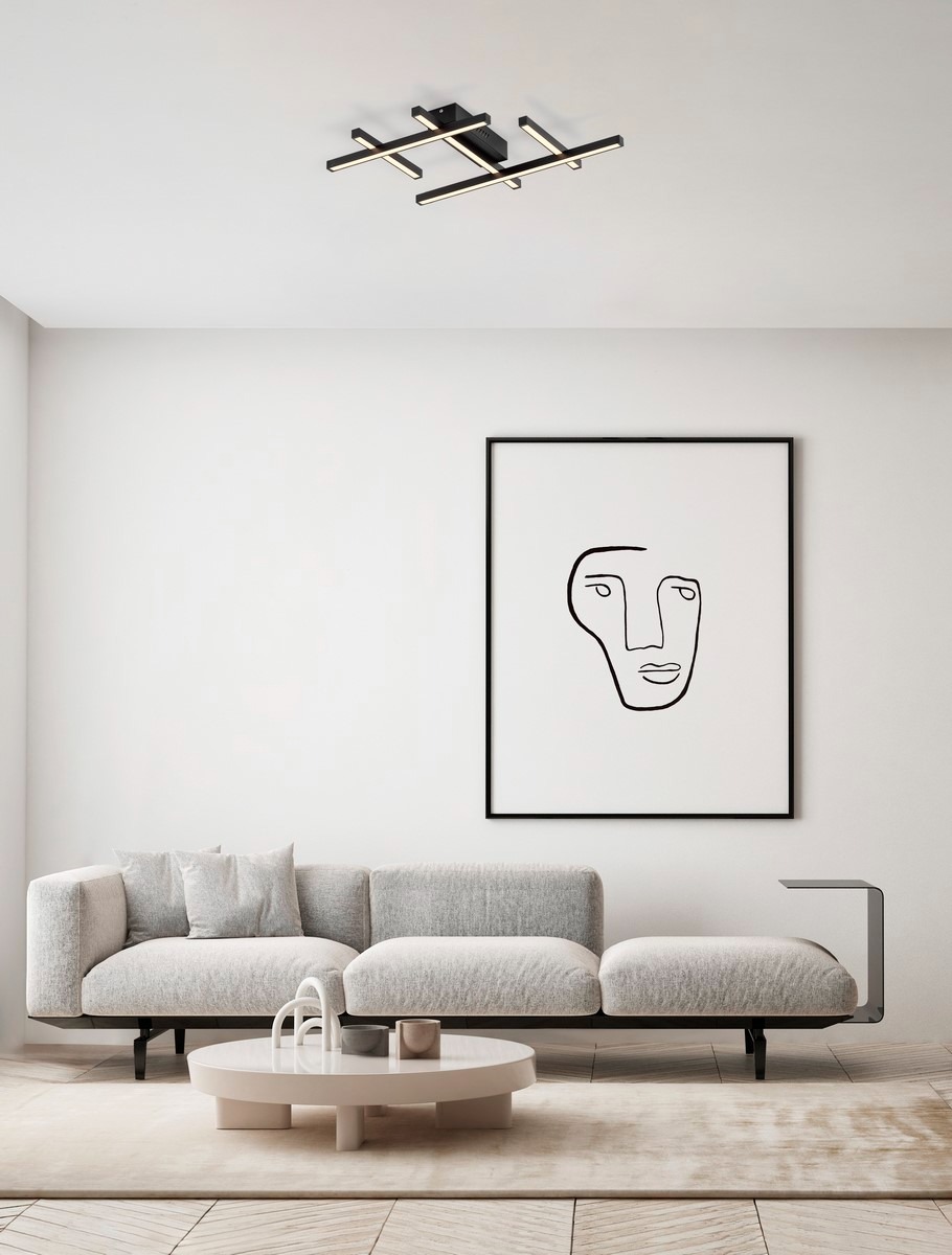 Czarna lampa sufitowa Tumbes z jedną żarówką LED 42W, o minimalistycznym designie z prostokątnymi ramionami, zamontowana na suficie. Tło jasne, w nowoczesnym wnętrzu z sofą i obrazem.
