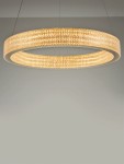 Złota lampa wisząca Yotau z jednym źródłem LED 70W, w kształcie okręgu. Posiada teksturowaną powierzchnię, emituje ciepłe światło. Zawieszona na cienkich linkach, idealna do nowoczesnych wnętrz. Tło w odcieniach szarości.