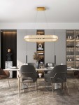 Lampa wisząca Yotau 1xLED 70W w kolorze złotym, o owalnym kształcie, zawieszona na cienkich linkach. W tle nowoczesna jadalnia z drewnianymi akcentami, szklanymi półkami i eleganckimi krzesłami. Złote detale podkreślają styl aranżacji.