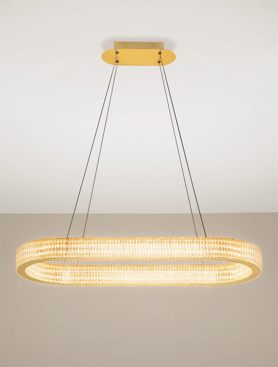 Lampa wisząca Yotau 1xLED 70W w złotym kolorze, o owalnym kształcie, zawieszona na cienkich linkach. Posiada kryształowe zdobienia, które odbijają światło, tworząc efektowną iluminację. Montowana do sufitu na prostokątnej podstawie.