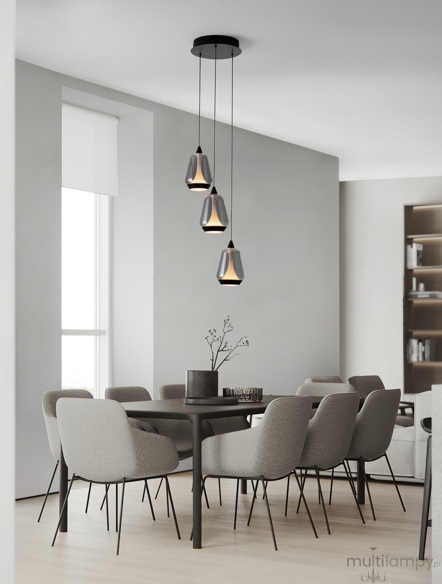 Lampa wisząca Rorizno z trzema kloszami, czarna z przydymionym szarym szkłem. Wisi na długich kablach, zawieszona na okrągłej podstawie. Idealna do nowoczesnych wnętrz, umieszczona nad stołem w jadalni. W tle szare krzesła i minimalistyczne aranżacje.