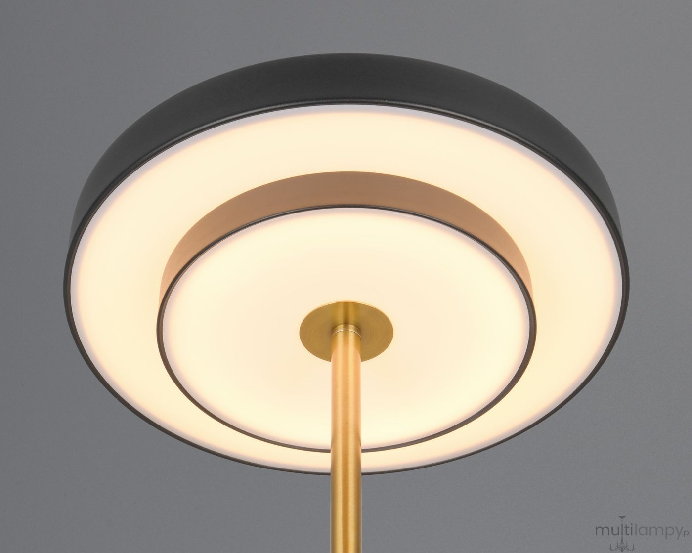 Lampa stołowa Keaton z czarnym, okrągłym kloszem i złotym stelażem. U góry znajduje się biały, okrągły dyfuzor LED o mocy 12W. Ujęcie z dołu ukazuje detale konstrukcji oraz eleganckie połączenie kolorów.