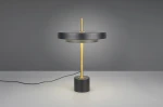Lampa stołowa Keaton w kolorze czarnym i złotym, z podstawą w kształcie walca. Posiada okrągły klosz oraz metalowy stelaż. Ujęcie frontalne, prezentujące całość lampy z widocznym przewodem zasilającym. Wbudowany moduł LED 12W.