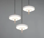 Lampa wisząca Keaton z trzema źródłami LED o mocy 30W, w kolorze szarym. Okrągłe klosze z białym wnętrzem i miedzianymi detalami, zawieszone na czarnych przewodach. Produkt umieszczony na szarym tle.