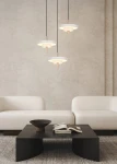 Lampa wisząca Keaton 3xLED 30W CCT w kolorze szarym z trzema okrągłymi kloszami, zawieszona na czarnych przewodach, w aranżacji nad czarnym stołem. Tło w neutralnym odcieniu, z jasnymi sofami w stylu minimalistycznym.