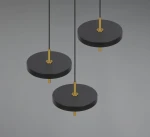 Lampa wisząca Keaton z trzema okrągłymi kloszami w kolorze czarnym, zawieszona na cienkich linkach. Elementy metalowe w kolorze złotym, minimalistyczny design. Klosze mają płaską formę, co nadaje nowoczesny charakter.