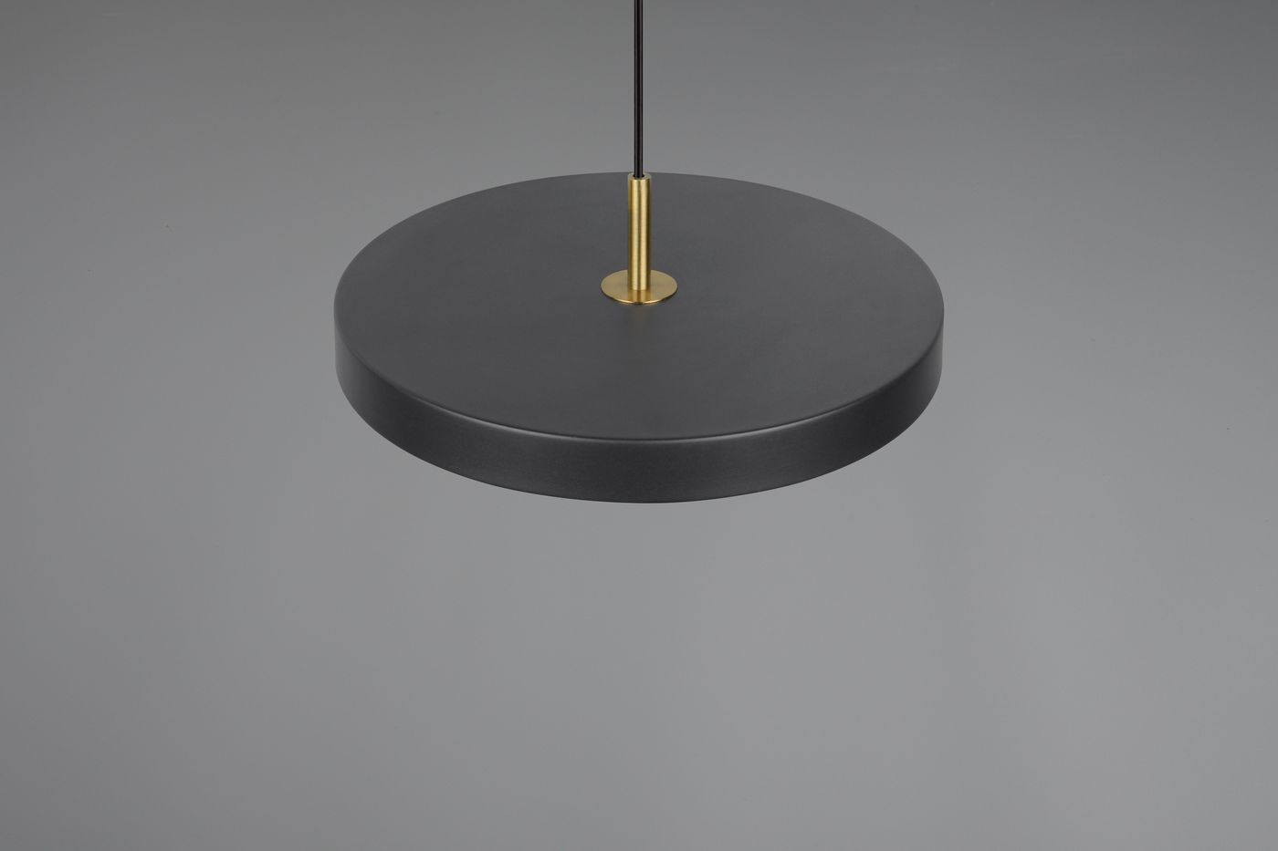 Lampa wisząca Keaton z czarnym, okrągłym kloszem i złotym mocowaniem. Ujęcie z dołu, prezentujące minimalistyczny design. Wbudowane oświetlenie LED o mocy 34,5W. Tło w odcieniach szarości, podkreślające elegancję lampy.