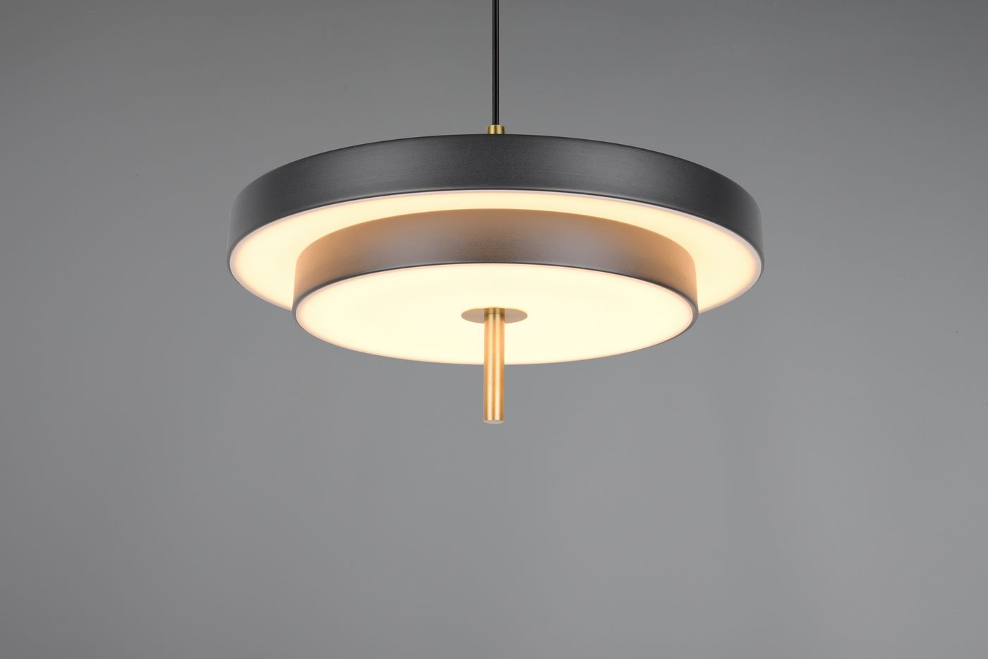 Lampa wisząca Keaton z jedną diodą LED o mocy 34,5W, w kolorze czarnym z elementami złotymi. Okrągła, zawieszona na cienkim kabelku, z dwoma pierścieniami – zewnętrznym matowym i wewnętrznym w kolorze białym. Tło szare.