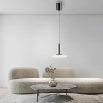 Lampa wisząca Pure Vitrum 1xLED 13W w metalicznym brązie, zawieszona na cienkim przewodzie, z okrągłym, białym kloszem. W tle widoczna jasna ściana oraz nowoczesna, tapicerowana sofa w neutralnym kolorze i okrągły stół z kamiennym blatem.