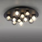 Lampa sufitowa Pure Popup w kolorze grafitowym, o okrągłej podstawie, z 11 żarówkami LED w szklanych kloszach. Zawiera pilot do zdalnego sterowania. Ujęcie z góry, montowana na suficie, z widocznymi źródłami światła.