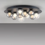 Grafitowa lampa sufitowa Pure Popup z pilotem, o średnicy 11xLED, z 10 szklanymi kloszami, zamontowana w sposób płaski. Klosze mają okrągły kształt, w kolorze przezroczystym, emitującym ciepłe światło. Prosta konstrukcja na jednolitym tle.