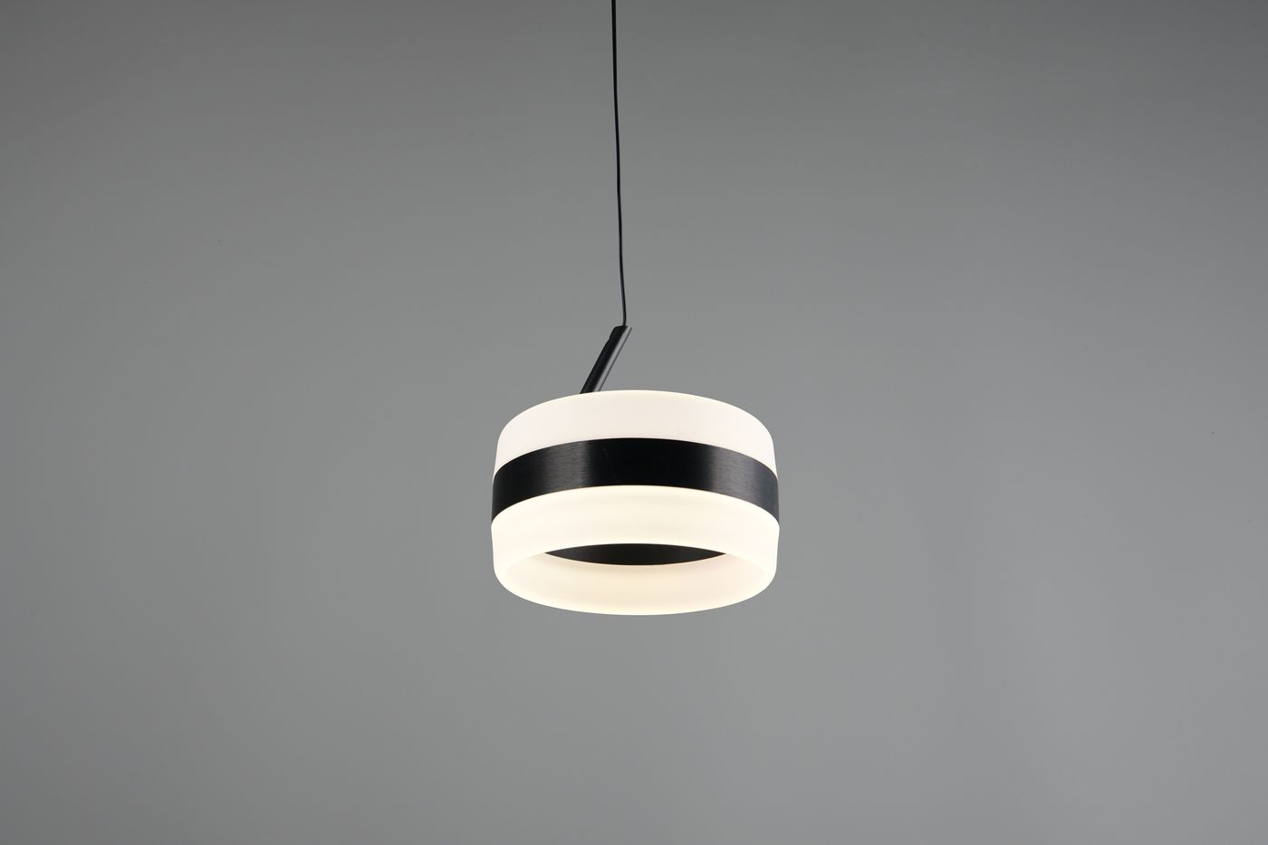 Lampa wisząca Dios w kolorze czarnym z białym kloszem, posiadająca jedną żarówkę LED 8W. Ujęcie z przodu, zawieszona na cienkim kablu. Klosz ma okrągły kształt z poziomą czarną wstęgą. Tło szare.