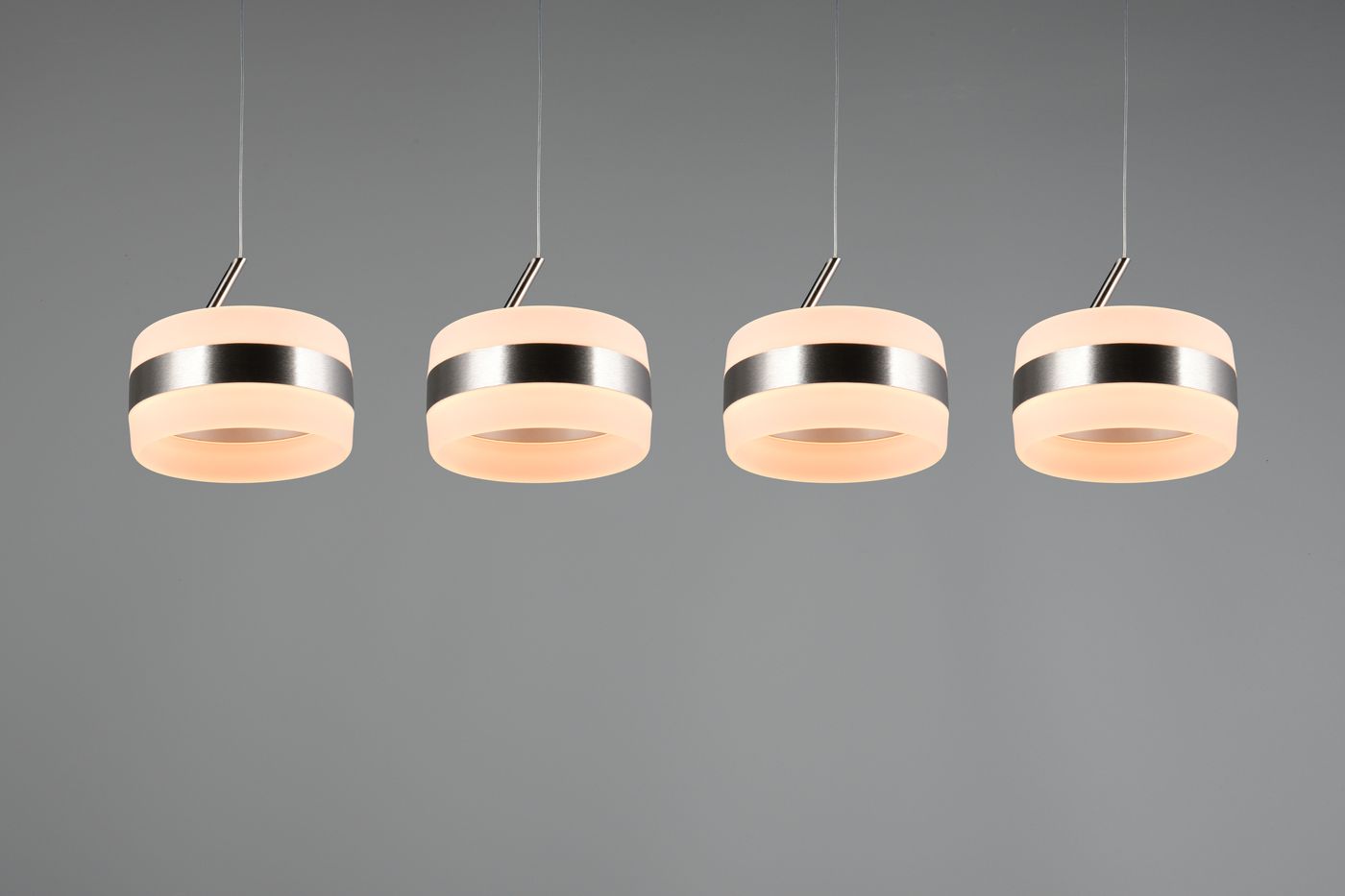 Lampa wisząca Dios z czterema okrągłymi kloszami w kolorze mlecznym, z metalowymi, niklowanymi detalami. Zawieszona na cienkich linkach, w nowoczesnym stylu, idealna do oświetlenia wnętrz. Klosze mają średnicę około 20 cm.