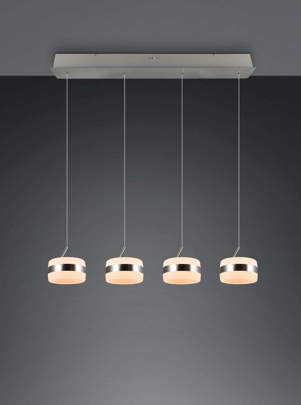 Lampa wisząca Dios z czterema okrągłymi kloszami LED, w kolorze niklowym. Klosze mają gładką, matową powierzchnię i są zawieszone na cienkich linkach. Produkt montowany do sufitu, umieszczony na ciemnym tle.