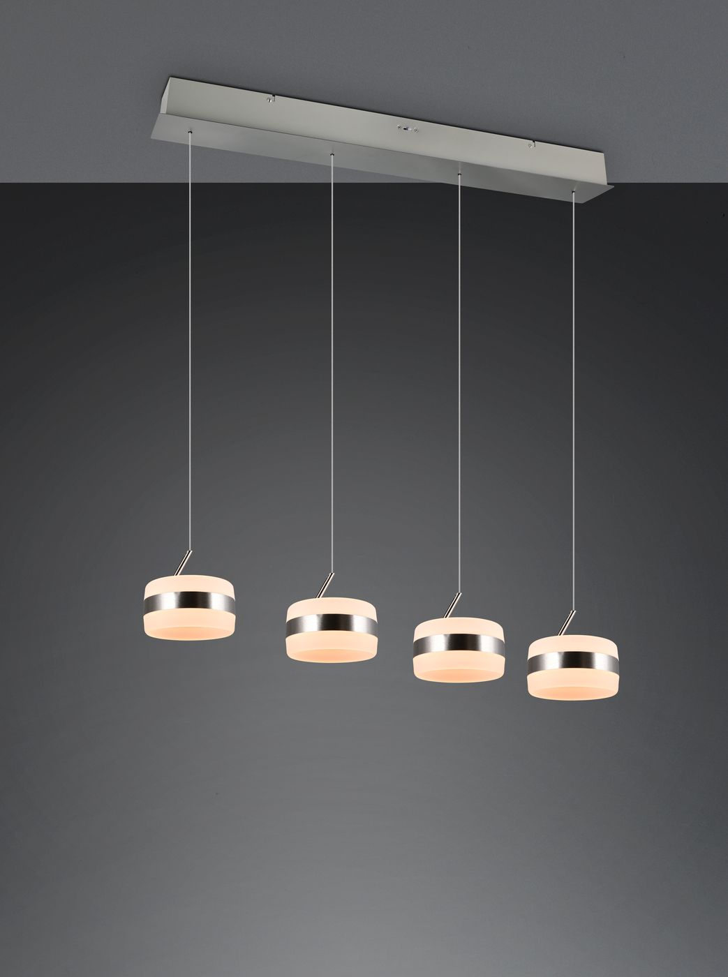 Lampa wisząca Dios z czterema okrągłymi kloszami LED w kolorze niklu. Klosze mają mleczny, lekko zaokrąglony kształt, zawieszone na cienkich linkach. Ułożona poziomo, na szarym tle, w minimalistycznym stylu.