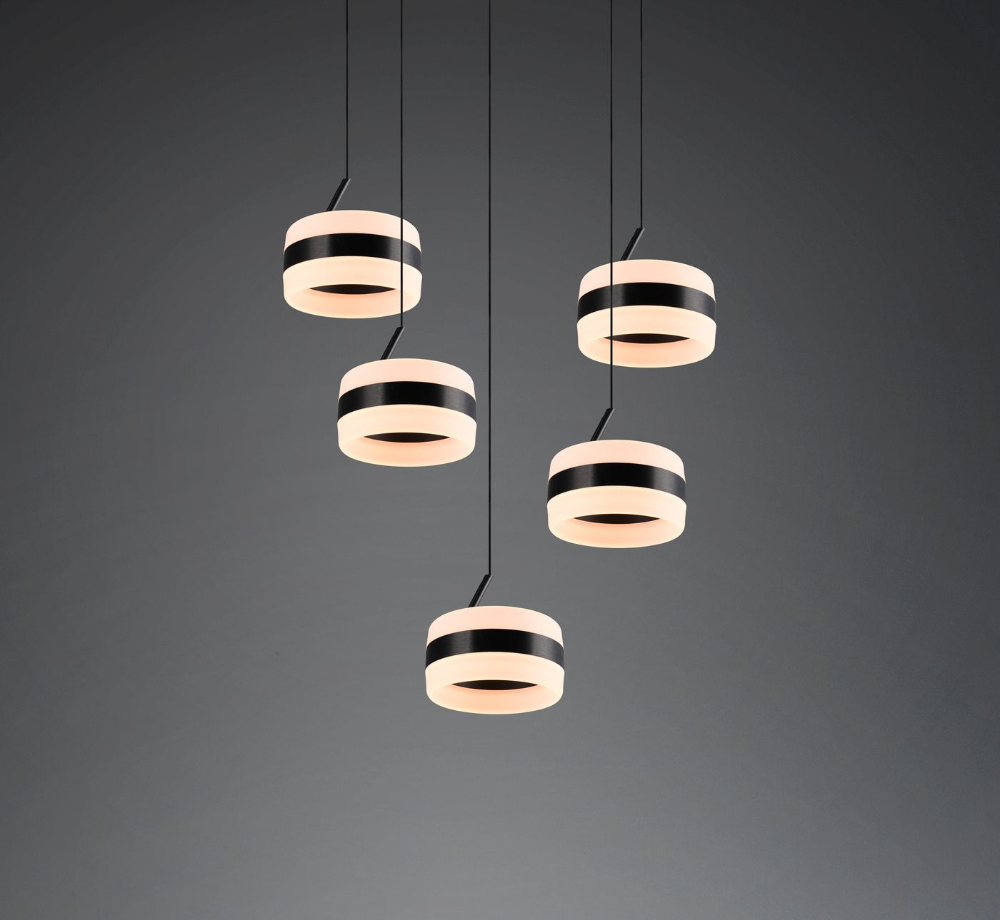Lampa wisząca Dios z pięcioma okrągłymi kloszami LED w kolorze czarnym z białymi paskami. Klosze zawieszone na cienkich przewodach, w nowoczesnym stylu, na ciemnym tle. Idealna do nowoczesnych wnętrz.