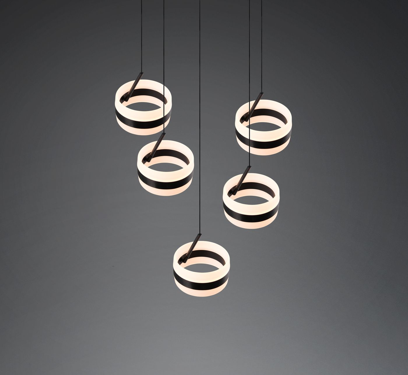 Lampa wisząca Dios z pięcioma okrągłymi kloszami LED w kolorze czarnym i białym. Klosze zawieszone na cienkich linkach, układają się w harmonijną kompozycję. Kąt ujęcia jest frontalny, na jednolitym ciemnym tle.
