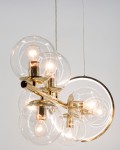 Lampa wisząca Galaxy z siedmioma oprawami E14 i jedną LED, w złotym wykończeniu. Składa się z przezroczystych szklanych kloszy w formie kul, umieszczonych na metalowej konstrukcji, z okrągłym elementem dekoracyjnym.