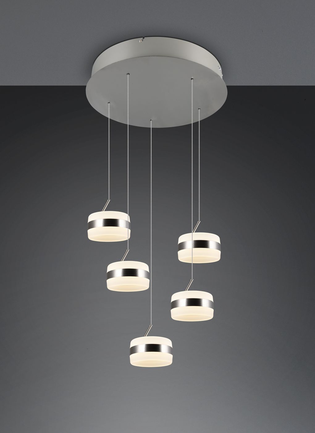 Lampa wisząca Dios z pięcioma okrągłymi kloszami LED w kolorze niklowym, zawieszona na cienkich linkach. Klasyczne wzornictwo z białymi, matowymi kloszami i metalowymi obręczami. Ujęcie z góry na szarym tle, z równym rozmieszczeniem elementów.