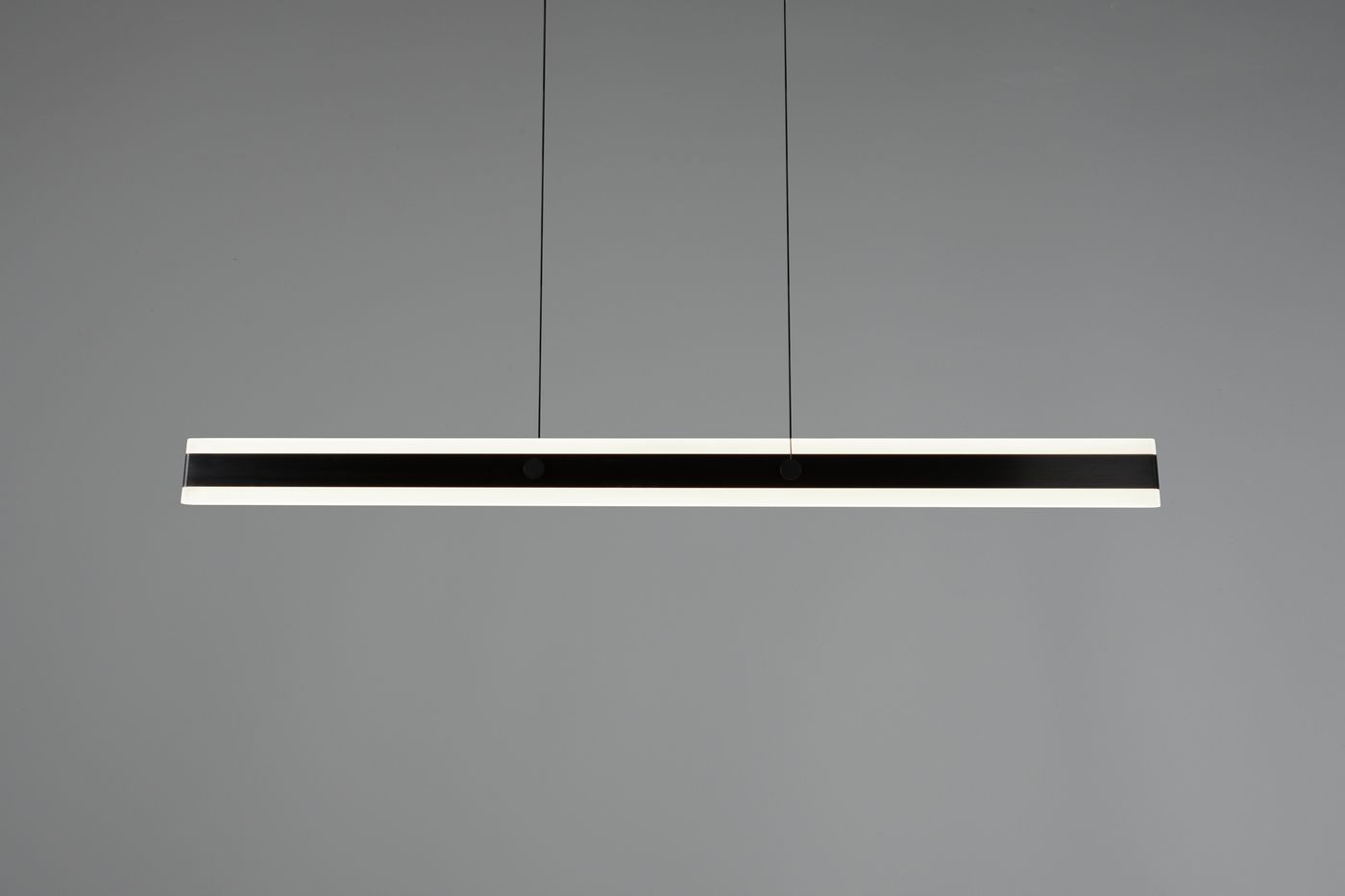 Lampa wisząca Arcola 1xLED 35W CCT w kolorze czarnym, w formie długiego prostokąta z białymi krawędziami. Zawieszona na cienkich linkach, z widocznymi detalami montażowymi. Tło szare, co podkreśla minimalistyczny design.