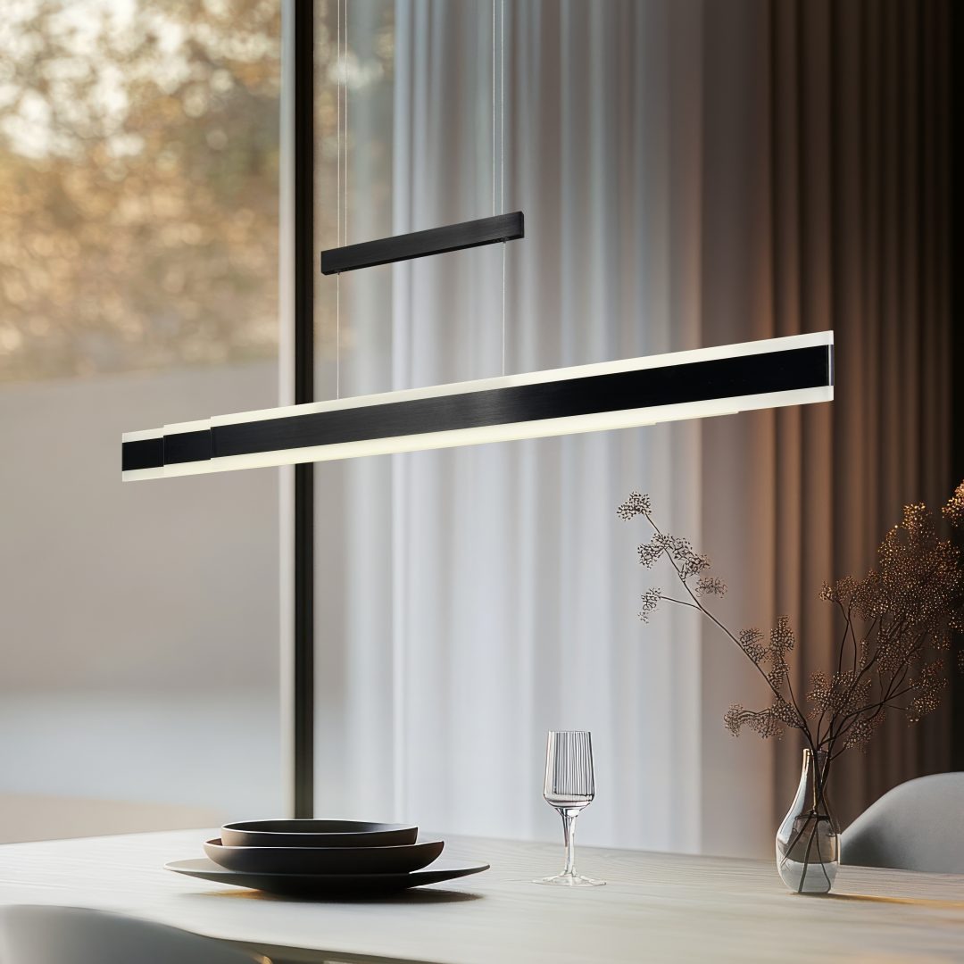 Lampa wisząca Arcola w kolorze czarnym, z jednym źródłem światła LED 45W CCT. Prosty, prostokątny kształt. Zawieszona nad stołem w jadalni, w otoczeniu talerzy i szklanek, z zasłonami w tle.