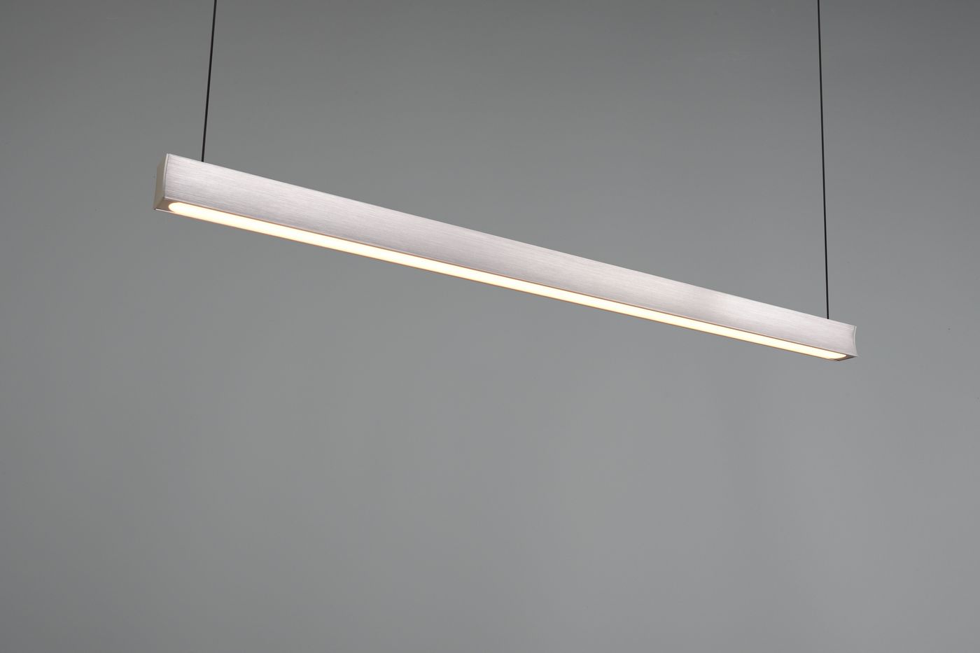 Lampa wisząca Wallace w kolorze czarnym i niklowym, o długości prostokątnej, zawieszona na cienkich linkach. Wyposażona w diodę LED 29W CCT, emituje jednolite światło. Tło szare, minimalistyczne.