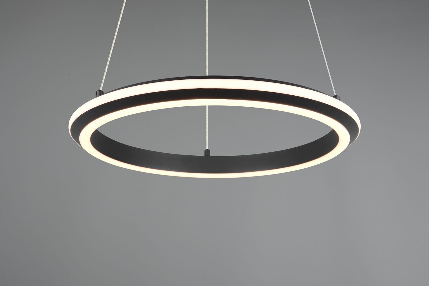 Lampa wisząca Amador w kształcie okręgu, czarna z białym podświetleniem LED 34W CCT. Zawieszona na cienkich linkach, z widocznym detalem na krawędzi. Tło szare, minimalistyczne.