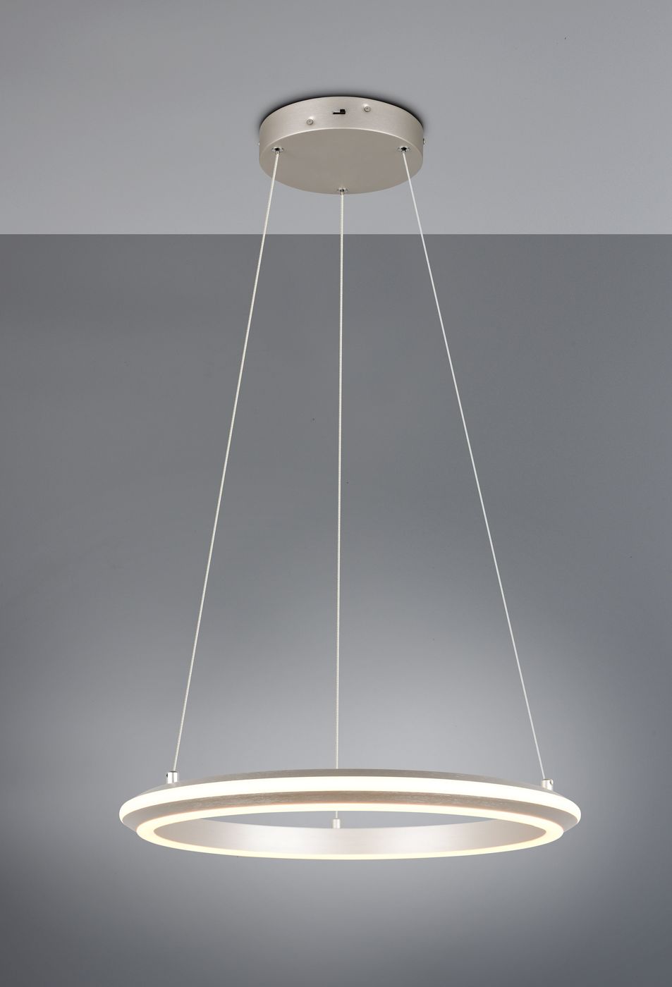 Lampa wisząca Amador z 1xLED 34W w kolorze niklowym, o okrągłym kształcie z dwiema wąskimi obręczami w odcieniach białego i ciepłego światła. Zawieszona na cienkich linkach, montowana do sufitu. Tło w odcieniach szarości.