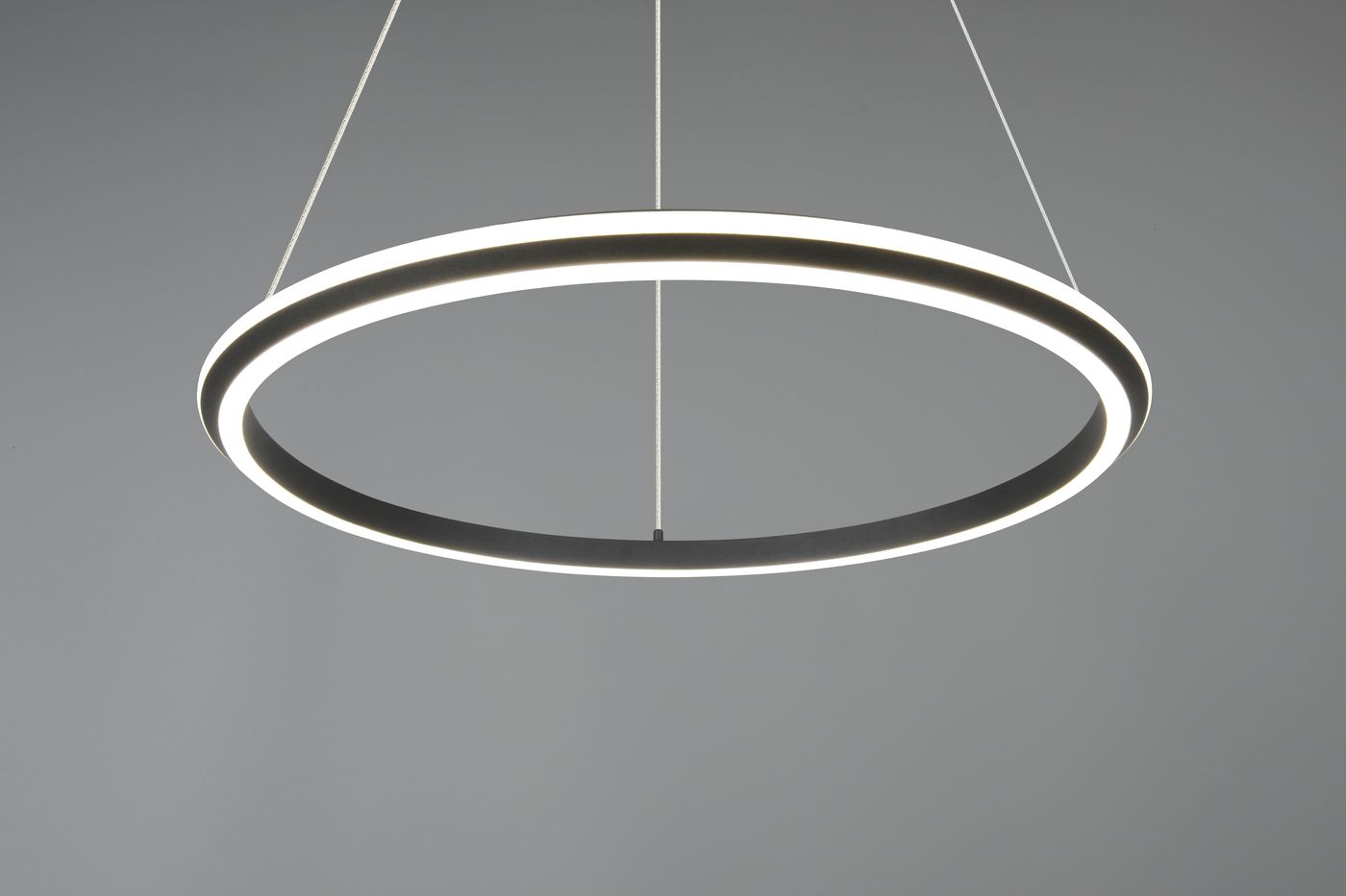 Lampa wisząca Amador 1xLED 48W CCT w kolorze czarnym, o okrągłym kształcie. Widoczny biały pierścień świetlny otaczający czarną obręcz. Zawieszona na cienkich linkach, na szarym tle. Idealna do nowoczesnych wnętrz.