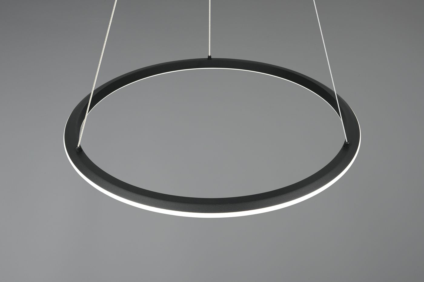 Lampa wisząca Amador w kolorze czarnym, o okrągłym kształcie, zawieszona na cienkich linkach. Posiada diodę LED 48W z funkcją CCT, emitującą światło wokół obrzeża. Ujęcie z góry, na jednolitym szarym tle.