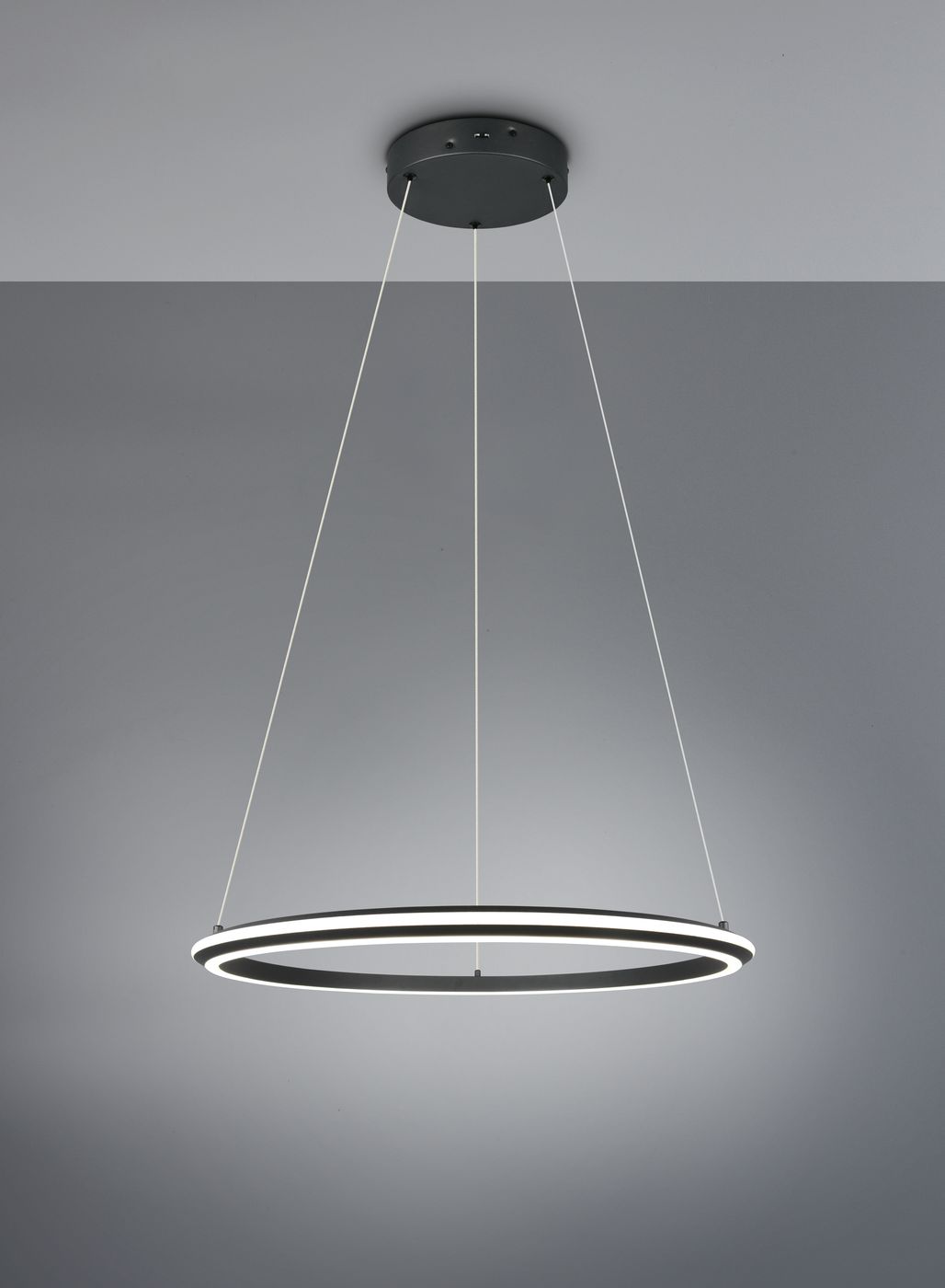 Lampa wisząca Amador 1xLED 48W CCT w kolorze czarnym, o okrągłym kształcie z białym podświetleniem. Zawieszona na cienkich linkach, montowana do sufitu. Tło w odcieniach szarości.